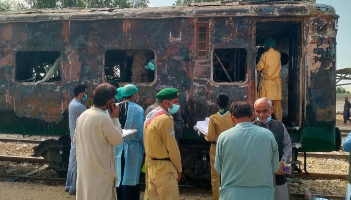 Security officials search for victims inside a burnt-out carriage following an overnight fire in the Karachi Express passenger train near Sukkur on April 27, 2023. — AFP