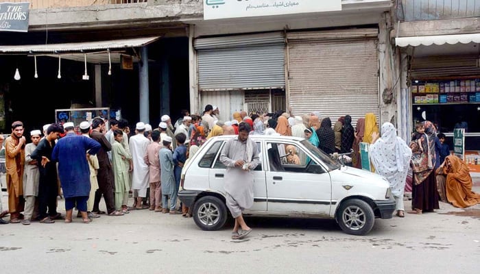 Citizens queue to purchase grocery items from a utility store in Peshawars Sethi Town on August 24, 2022. — APP/File