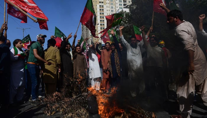 Pakistan Tehreek-e-Insaf party activists and supporters of former prime minister Imran Khan shout slogans next to a fire as they block a road during a protest against his arrest in Karachi on May 9, 2023. — AFP/File