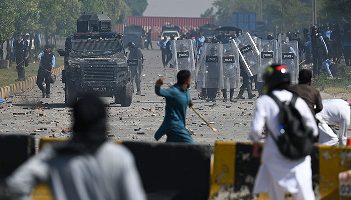 TOPSHOT - Pakistan Tehreek-e-Insaf (PTI) party activists and supporters (foreground) of former Pakistan´s Prime Minister Imran Khan clash with police during a protest against the arrest of their leader, in Islamabad on May 10, 2023. —AFP