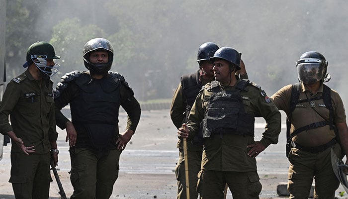 Policeman stand guard as Pakistan Tehreek-e-Insaf party activists and supporters of former Pakistan´s Prime Minister Imran Khan protest against the arrest of their leader, in Lahore on May 11, 2023. The army was on standby across Pakistan on May 11 after the arrest of former prime minister Imran Khan triggered two days of violent protests by his supporters.—AFP
