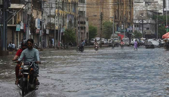 Commuters drive through a flooded street after heavy monsoon rainfall in Karachi on July 25, 2022. — AFP