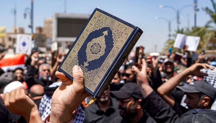 A demonstrator holds a copy of the Holy Quran during a rally in Iraqs central shrine city of Kufa after a Friday prayer denouncing the holy books burning in Sweden on 21 July 2023. — AFP