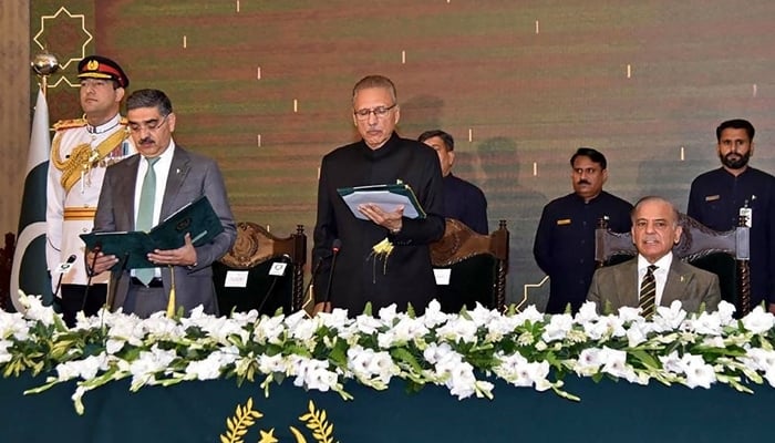 This photograph taken on August 14, 2023 shows President Arif Alvi (3L) administering oath to Anwaar-ul-Haq Kakar (2L) as caretaker PM during an oath-taking ceremony while outgoing PM Shehbaz Sharif (R) looks on at President House in Islamabad. — AFP