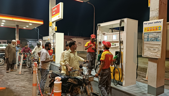 This picture taken on August 12, 2023, shows people waiting to get fuel in their motors bikes at a filling station in Hub River Road, Karachi. — Geo.tv