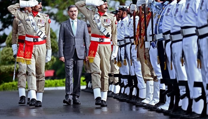 In this photograph taken on August 14, 2023, shows Pakistans newly appointed caretaker PM, Anwaar-ul-Haq Kakar (c) while being presented with a guard of honor at the Presidents House in Islamabad. — PID