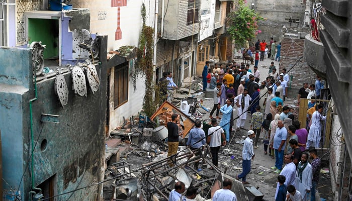 Police officials and residents stand amid debris beside the torched Saint John Church in Jaranwala on the outskirts of Faisalabad on August 17, 2023. — AFP
