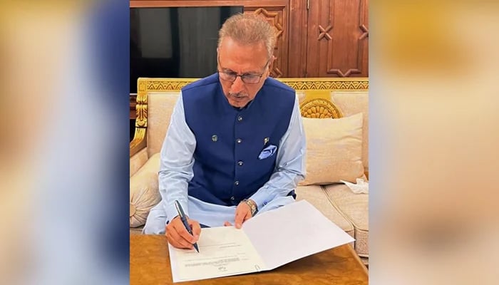This photograph released on August 10, 2023, shows President Arif Alvi signing the dissolution of the National Assembly, in Lahore. — PID