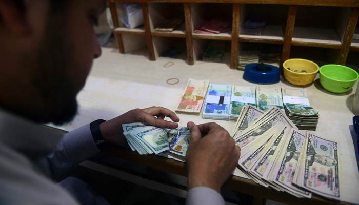A dealer counts US dollars at a money exchange market in Karachi on January 26, 2023. — AFP