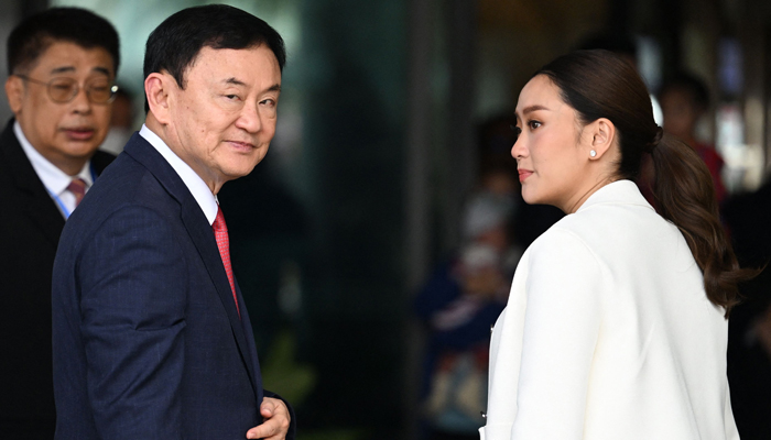 Former Thai Prime Minister Thaksin Shinawatra greets his supporters next to his daughter Paetongtarn Shinawatra (R) after landing at Bangkoks Don Mueang airport on August 22, 2023. — AFP