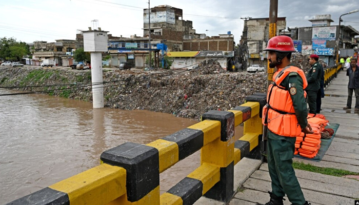 Rescue workers monitor the flood situation at a bridge over a stream in Rawalpindi, Pakistan, on July 7, 2023. — AFP