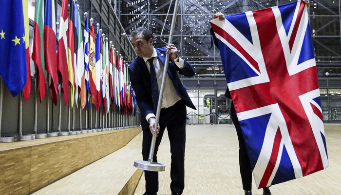 EU Council staff members remove the UK flag from the European Council building in Brussels on Brexit Day, January 31, 2020. — AFP