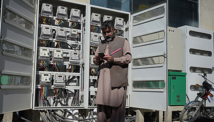 An employee of the Islamabad Electric Supply Company (IESCO), takes a meter reading with his smartphone at a commercial building in Islamabad. — AFP/File