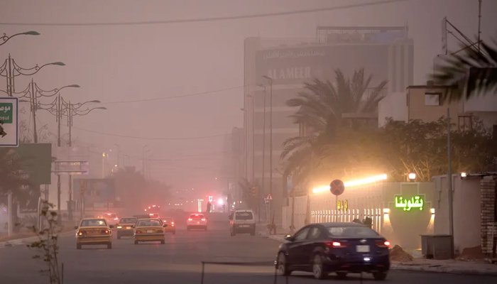 Vehicles drive down a road in Baghdad as thick dust blankets the city, on March 31, 2023. — AFP