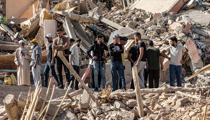 People stand by the rubble of a collapsed building in the aftermath of the deadly 6.8-magnitude September 8 earthquake, in the village of Imi NTala near Amizmiz in central Morocco on September 10, 2023. — AFP