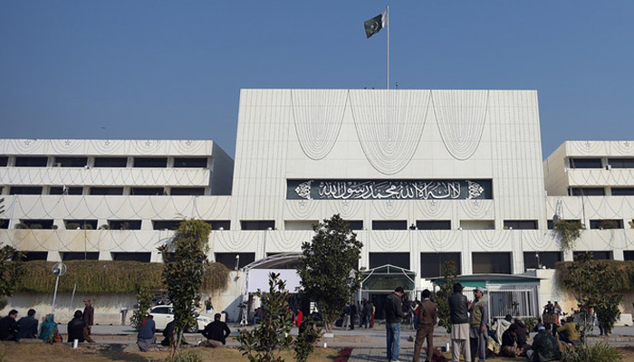 Pakistani security and media officials gather in front of the Parliament House building in Islamabad. — AFP/File
