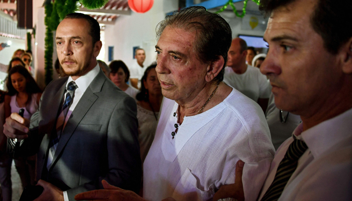 Brazilian spiritual healer Joao Teixeira de Faria (C), known as Joao de Deus is escorted by supporters, upon arrival at his healing centre Casa de Dom Inacio de Loyola, in Abadiania on December 12, 2018. — AFP