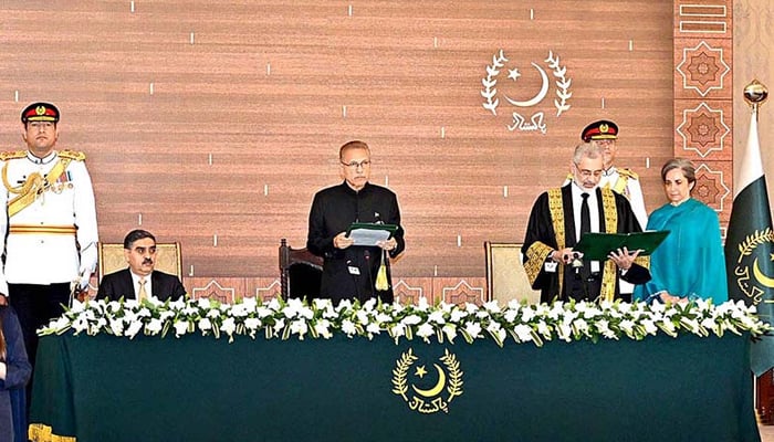 President Arif Alvi (c) while administering the oath to the new CJP Justice Qazi Faez Isa (right, standing with his wife) with PM Kakar looking toward the audience on September 17, 2023. — APP
