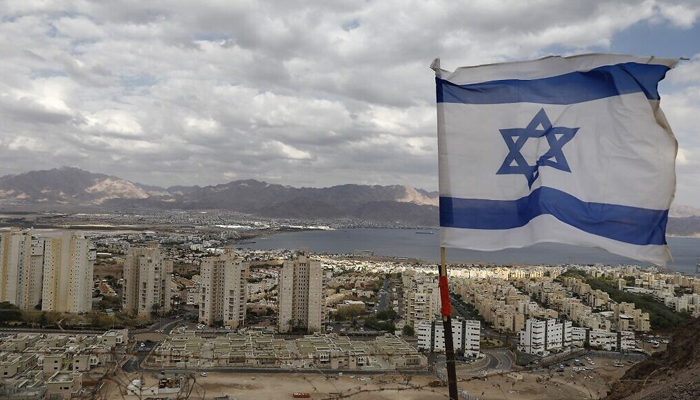 An Israeli flag flutters as the Red Sea resort city of Eilat and Jordans Red Sea resort city of Aqaba are seen in the background, on April 17, 2020. — AFP