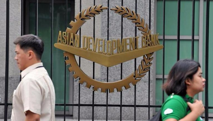Pedestrians walk past a logo of the Asian Development Bank (ADB) displayed outside its headquarters in Manila, Philippines. — AFP/File