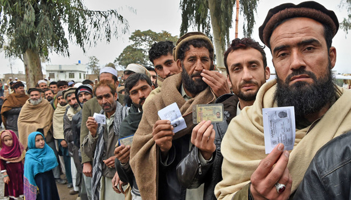 Afghan refugees queue up in Peshawar with identity cards in hand. — AFP/File
