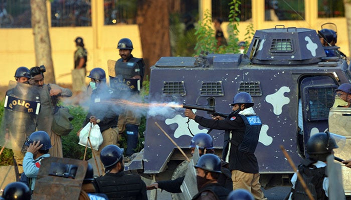 A policeman (C) fires a tear gas shell towards protestors. — AFP/File