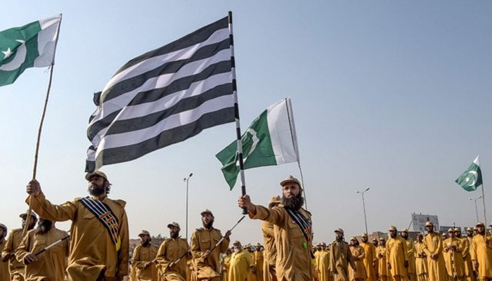 Workers of Jamiat Ulema-e-Islam-Fazl (JUIF) can be seen standing still holding the party flag. — AFP/File