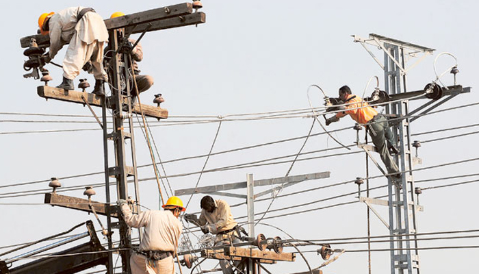 Pakistani technicians work on high-voltage power lines in Lahore. — AFP/File