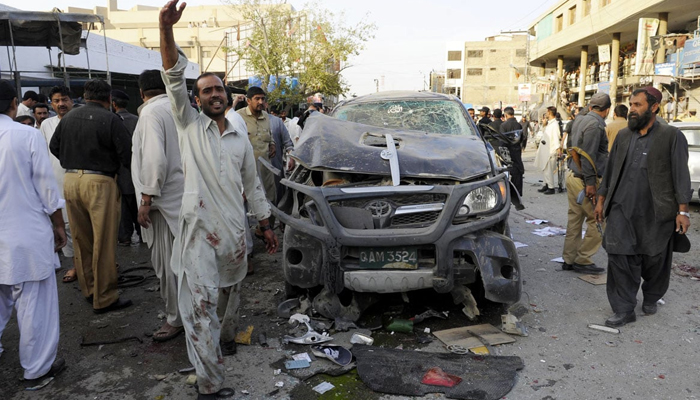 People gather at the site of a bomb blast where a bicycle bomb tore through a crowded market area near a police station in Quetta. — AFP