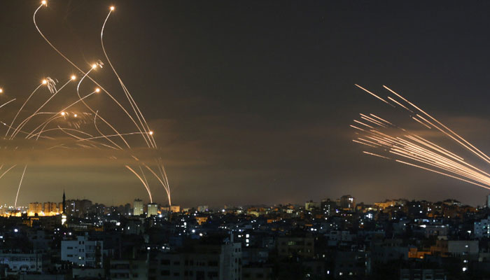 Israels Iron Dome defence system and rockets launched from Beit Lahia in the Gaza Strip rise into the night sky on May 14, 2023. — AFP