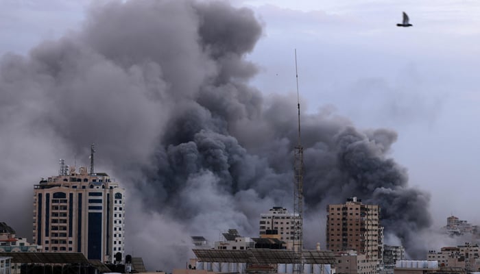 A black plume of smoke billows behind highrise buildings during an Israeli airstrike in Gaza City on October 9, 2023. — AFP
