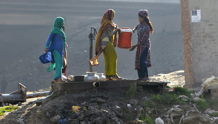 Photo of women filling water in large containers. — AFP