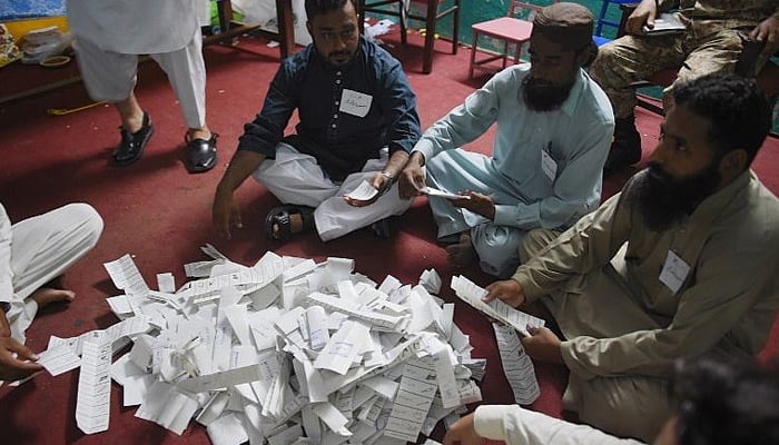 Pakistani election officials count ballots after polls closed at a polling station in Rawalpindi on July 25, 2018. — AFP