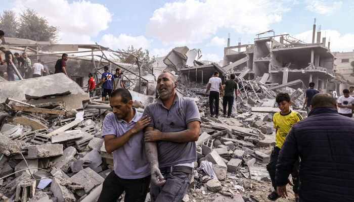 A Palestinian reacts as he is helped across the rubble following an Israeli airstrike on buildings in Rafah, in the southern Gaza Strip on October 17, 2023. — AFP