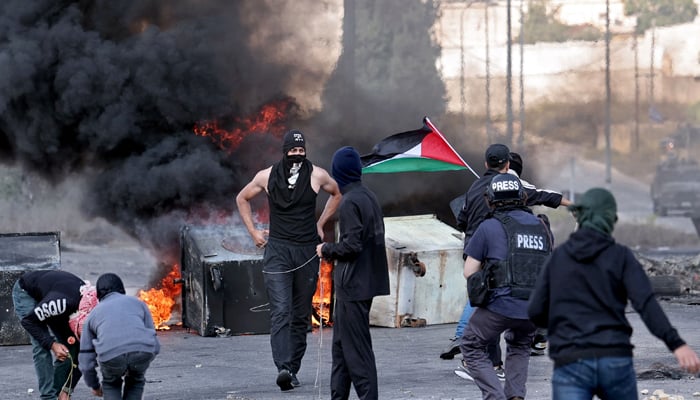 Palestinians use slingshots to throw stones towards Israeli soldiers during a demonstration in Ramallah, in the occupied West Bank on October 18, 2023. — AFP