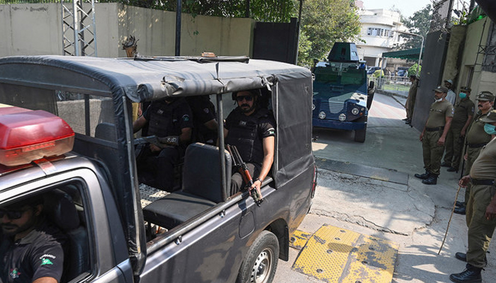 A police car escorts an armed vehicle leaving the court premises in Lahore. — AFP/File