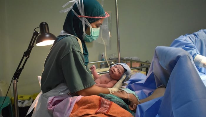 A healthcare person holding a new born baby. — AFP/File