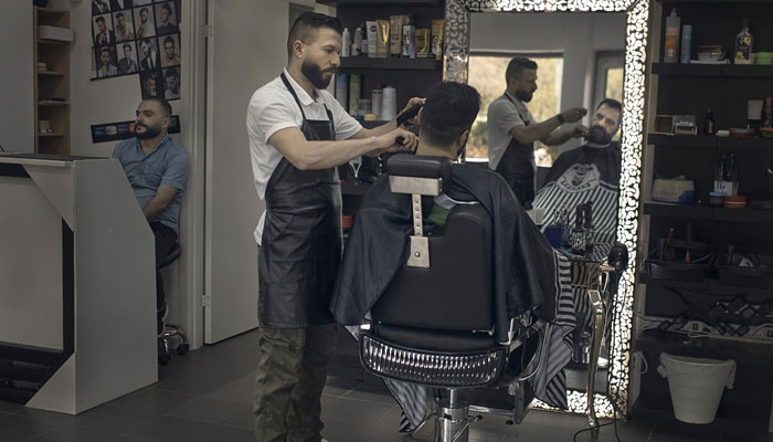Hairdresser Hasan Derek, 36, from Syria, cuts the hair of a customer in Akalla, Rinkeby-Kista borough, Stockholm, Sweden, April 28, 2020. Daily Sabah