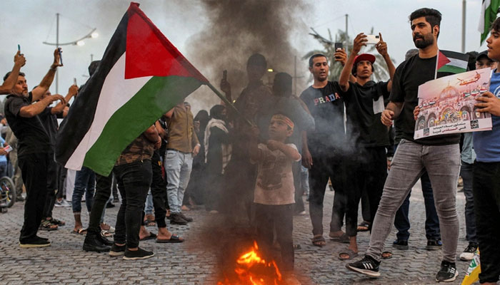 A young protester waves a Palestinian flag before a bonfire during a demonstration in solidarity with the Palestinian people in the Gaza Strip, in Iraqs southern city of Basra on October 20. Photo : AFP