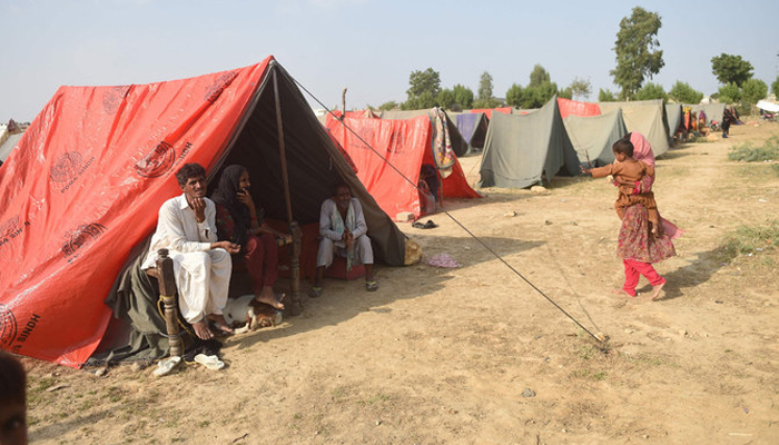 An internally displaced flood-affected family sits in a tent at a makeshift camp in Jamshoro district of Sindh province on September 26, 2022. — AFP