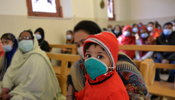 A child is wearing a mask among other people in Rawalpindi on December 20, 2020. — AFP