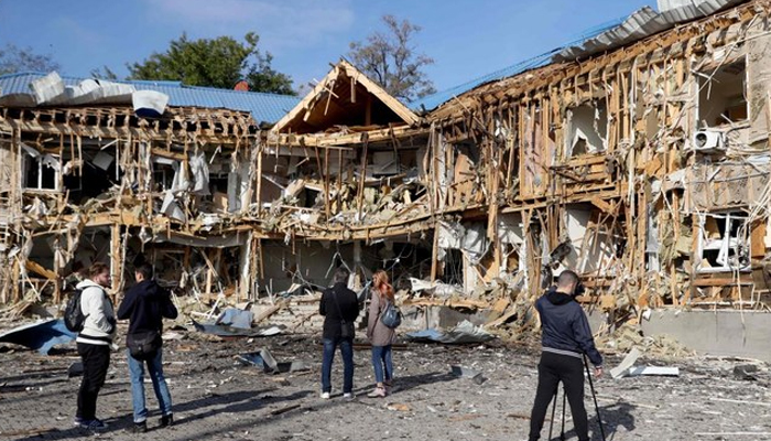 People and media look at a yacht club damaged as a result of falling remains of a Russian drone shot down in Odesa on October 17, 2023. — AFP