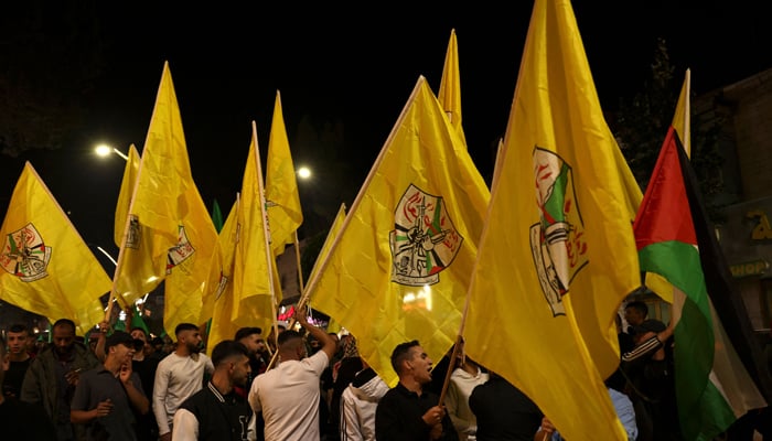 Palestinian wave yellow Fatah flags during a protest by supporters of Fatah and the Hamas movements, as people rally against the Israeli military strikes on the Gaza Strip, on October 22, 2023, in the occupied West Bank. — AFP