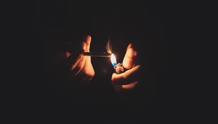 A representational image of a person lighting up a cigarette. — Unsplash/File