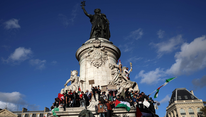 Protestors hold placards and Palestinian flags as they gather around the statue Le Triomphe de la Republique during a demonstration calling for peace in Gaza, in Paris, on October 22, 2023. — AFP