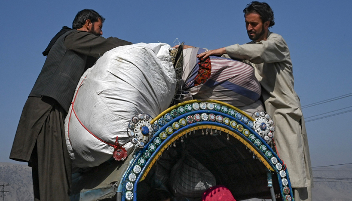 Afghan nationals travelling with their families secure their belongings on a vehicle in the Jamrud area of Khyber district on October 6, 2023, as they return to Afghanistan. — AFP