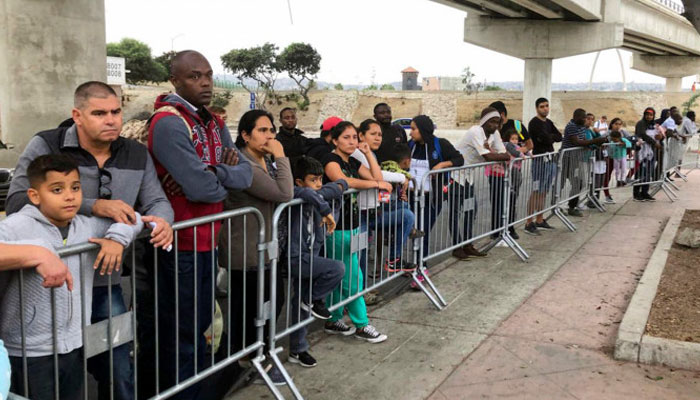 In this September 26, 2019 file photo, asylum seekers, in Tijuana, Mexico, listen to names being called from a waiting list to claim asylum at a border crossing in San Diego. The Business Standard