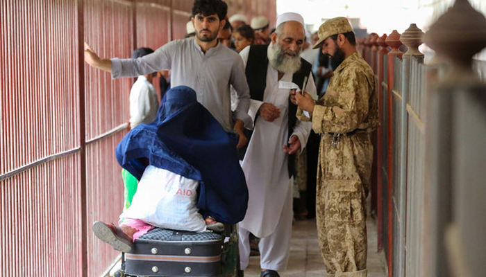 Afghans cross into Pakistan while security personnel stands guard at the Pakistan-Afghanistan border in Torkham on September 15, 2023. — AFP