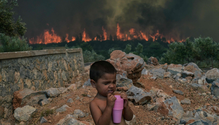 A child reacts as a wildfire burns in the village of Agios Charalabos, near Athens, July 18, 2023. — AFP