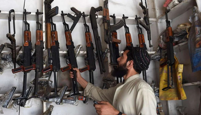 An arms seller in Darra Adamkhel picks an assault rifle from a shelf at his shop. — AFP/File